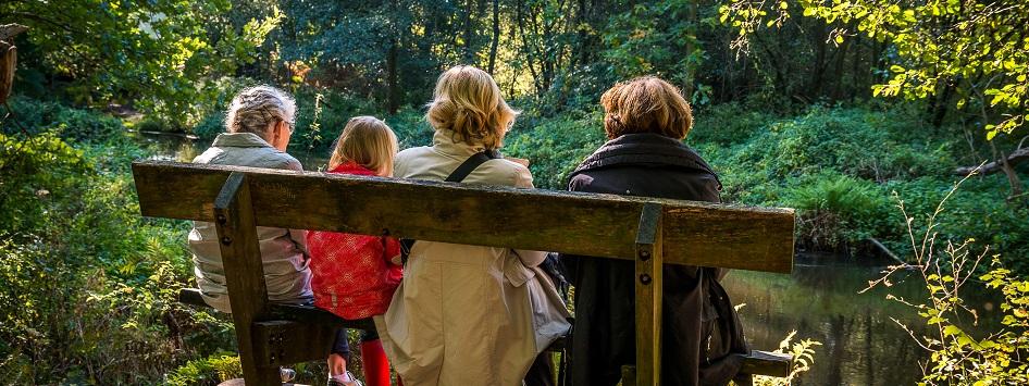 Familie zit op een bankje in de natuur in de herfst