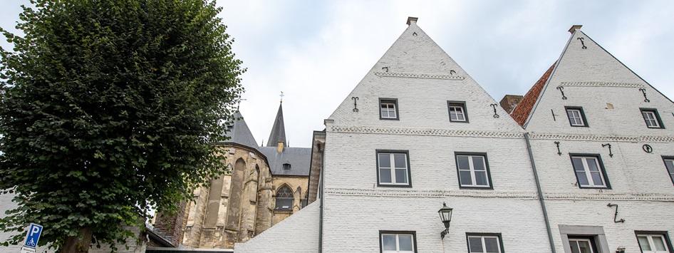 Twee witte huizen met op de achtergrond de Abdijkerk van Thorn