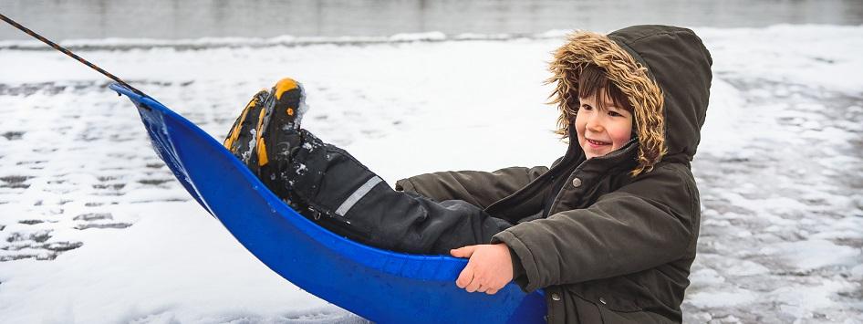 Kind zit op de slee in de winter