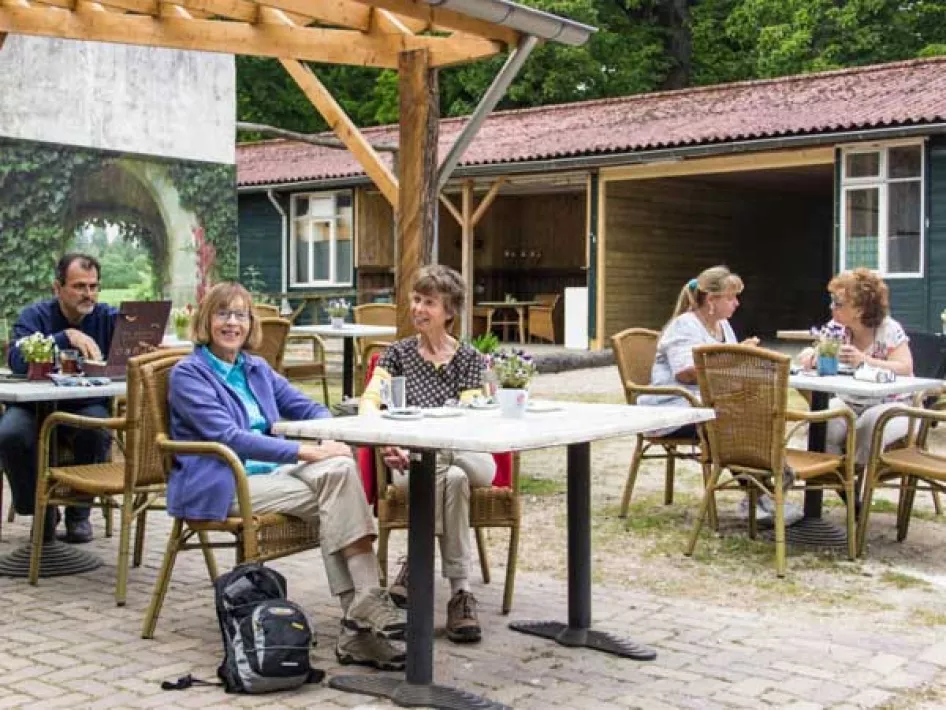 Mensen zitten op het terras van de Gasterij te genieten van een hapje en een drankje