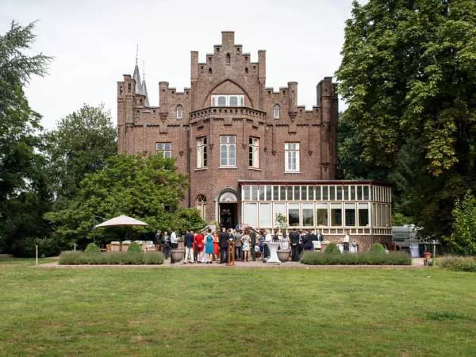 Buitenaanzicht van Kasteel Aerwinkel waar een receptie aan de gang is in de tuin