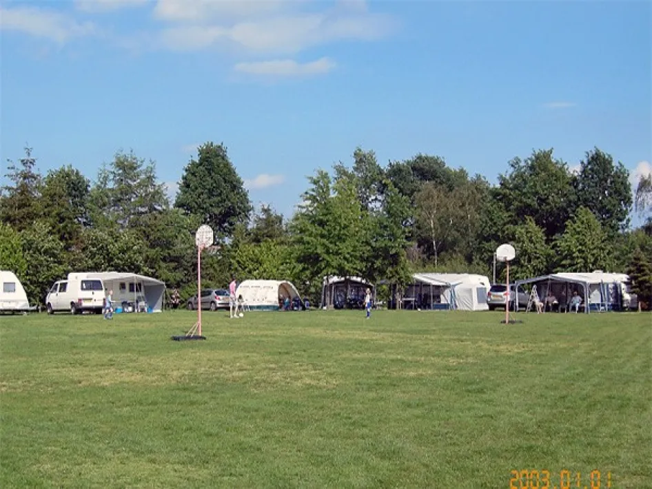 Großzügige Rasenfläche mit Wohnwagen und Vorzelten auf dem Campingplatz Straoterhof, umgeben von Bäumen und ruhiger Natur.