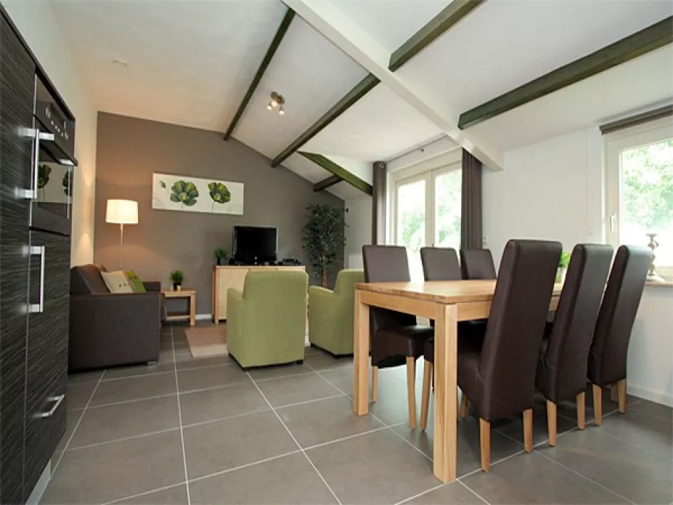 Woonkamer van het vakantiehuis met eettafel, zithoek en zicht op de tuin