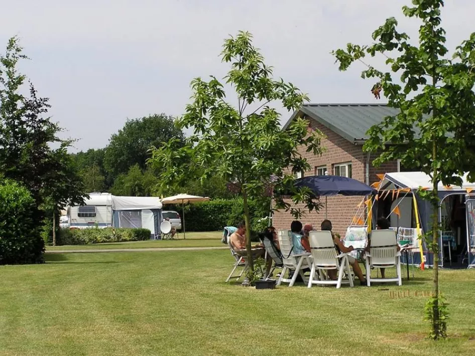 Kampeerders zitten aan de tafel voor de caravan op Camping 't Vossenveld