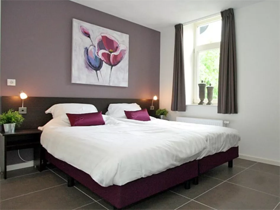 Slaapkamer met twee eenpersoonsbedden en kunst aan de muur