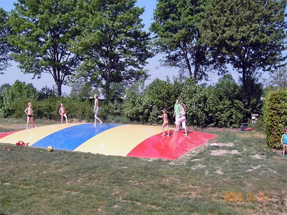 Kinder spielen auf einer farbenfrohen Hüpfburg im Freien auf dem Campingplatz Straoterhof, mit Bäumen im Hintergrund.