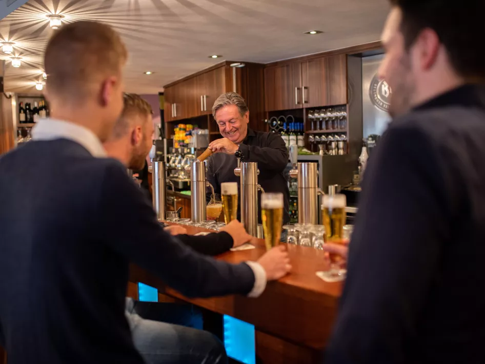 Men drink a beer at the bar of Gotcha! in WeertMannen drinken een biertje aan de bar van Gotcha!