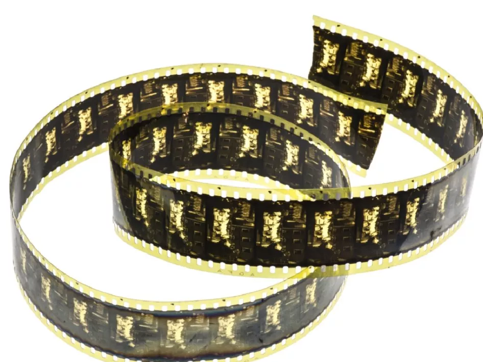 De afbeelding toont een stuk filmrol met donkere frames en perforaties aan de zijkanten, die symbool staan voor de vroege filmgeschiedenis. Dit verwijst naar de films van pater Simon Buis SVD, die in de jaren 1920 het missie- en cultuurleven op het Indonesische eiland Flores vastlegde. Deze filmrol vormt een belangrijk historisch document van de SVD-missies.