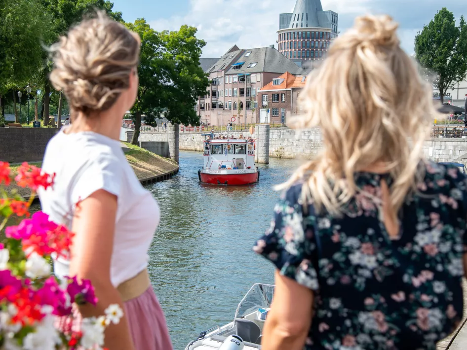 Twee vrouwen kijken naar de rondvaartboot van rederij de Corporaal