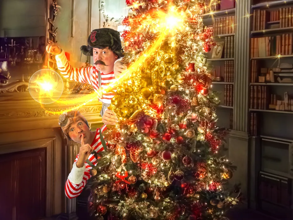 Willem Hoeben en Alex Helmers schuilend achter een versierde kerstboom