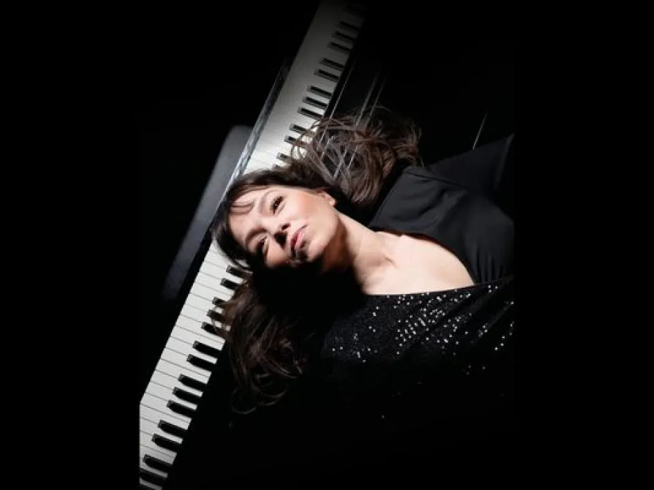 Portret van Linda Smeets liggend bij een piano, met een verstilde uitstraling en donkere achtergrond.