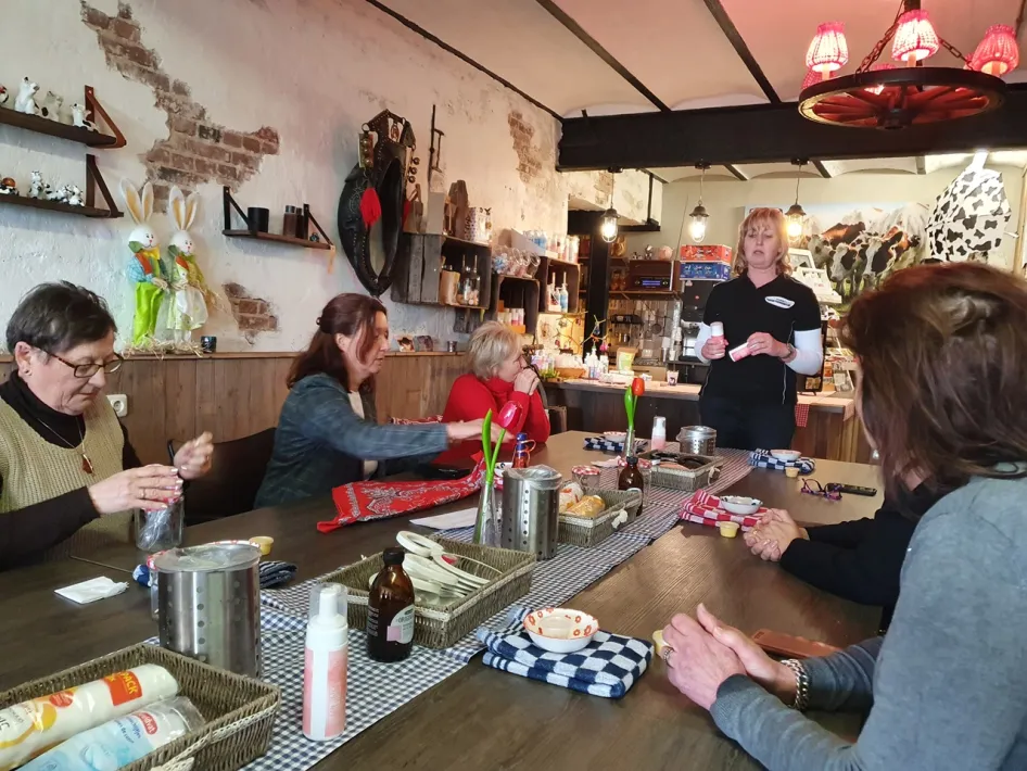 Frauen nehmen an einem Kreativ-Workshop an einem langen Tisch im ländlichen Workshop-Raum des Hobbyschuurtje teil.