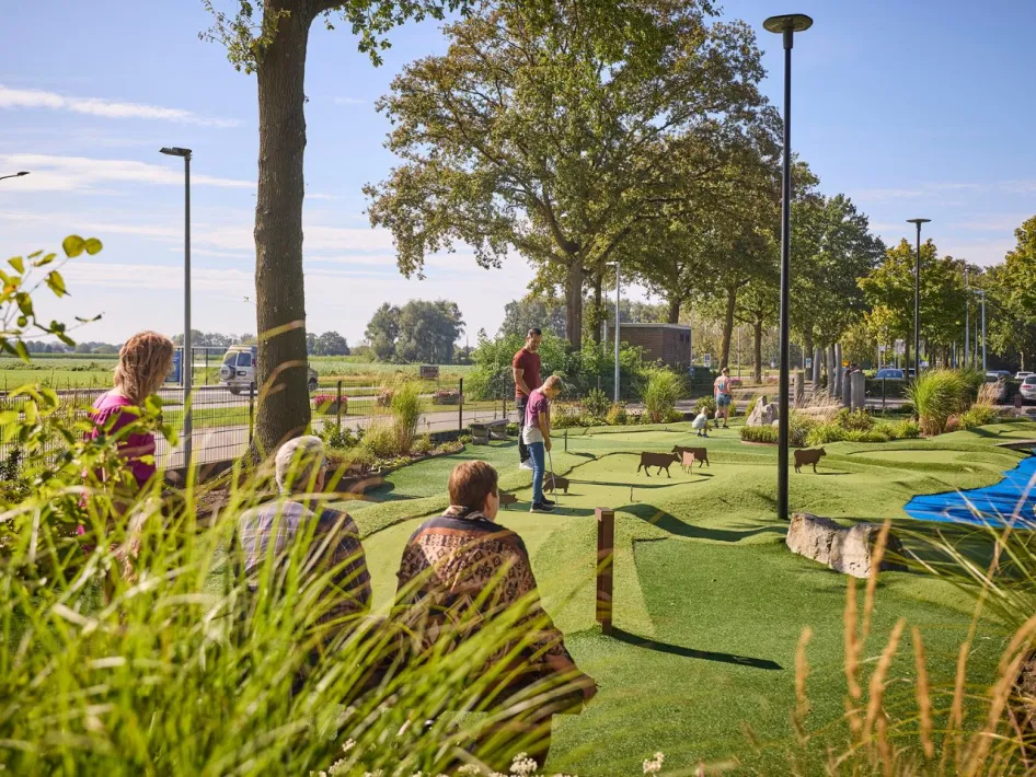 Gezin speelt samen Adventure golf bij de Leistert, op een speels aangelegd parcours met dierenfiguren en groene banen.