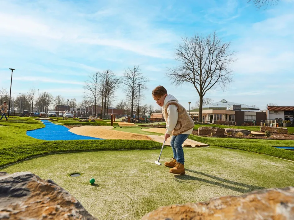 Jongen richt zich op de hole tijdens een potje minigolf op het fraai aangelegde Adventure golf terrein.