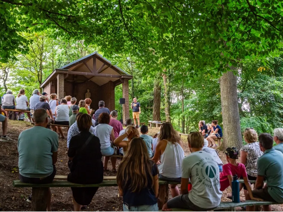 Limburg Festival waar allemaal mensen zitten op bankjes, gedraaid naar een open huisje