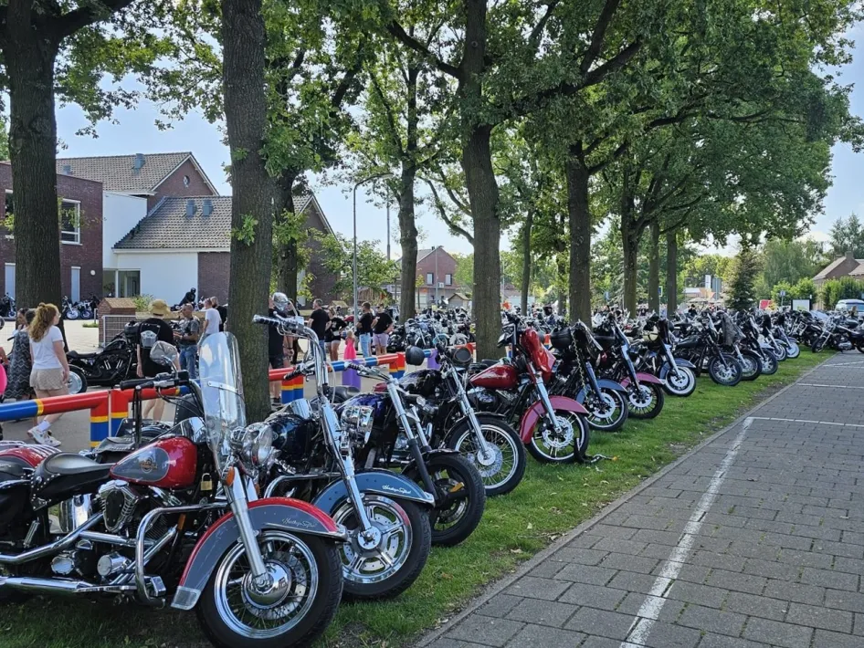 Rijen met glimmende motoren onder de bomen tijdens American Eagle Day in Weert, met bezoekers die rondlopen en de voertuigen bewonderen.