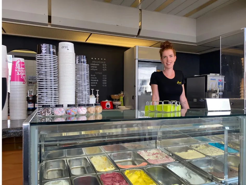 Das Innere von Anne's Ice Cream & Coffee Salon mit einem lächelnden Mitarbeiter hinter der Eisvitrine voller handwerklich hergestellter Eiskugeln.