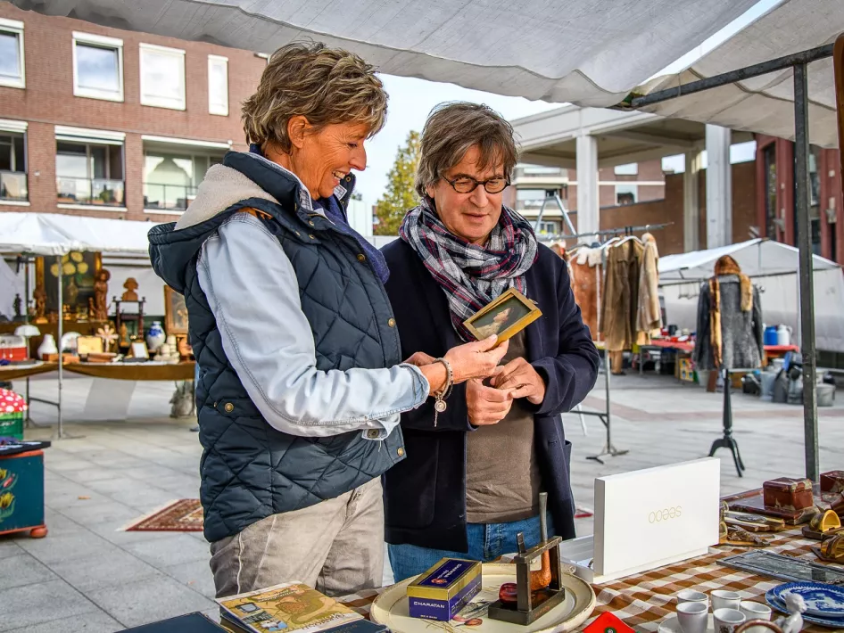Vrouw en man bekijken een antiek potretje op de Antiek- en brocante markt in Roermond