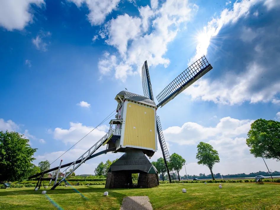 Aurora windmill in Baexem in the open landscape of Leudal with turning blades under a blue sky with sun and clouds