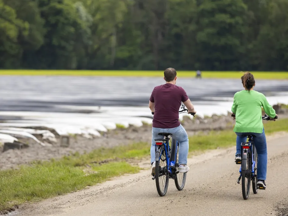 Two cyclists ride along vast asparagus fields during the Asparagus Route Leudal, overlooking the open landscape