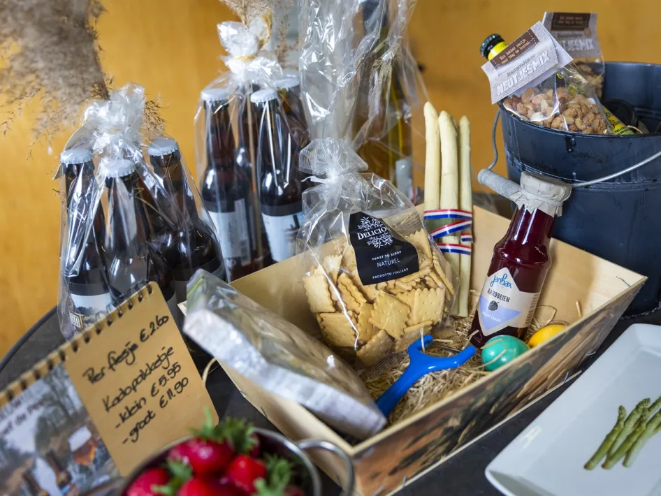 Geschenkkorb mit regionalen Produkten, Spargel, Soße und Flaschen in einer Holzkiste bei Spargel Hofladen Oppe Haes