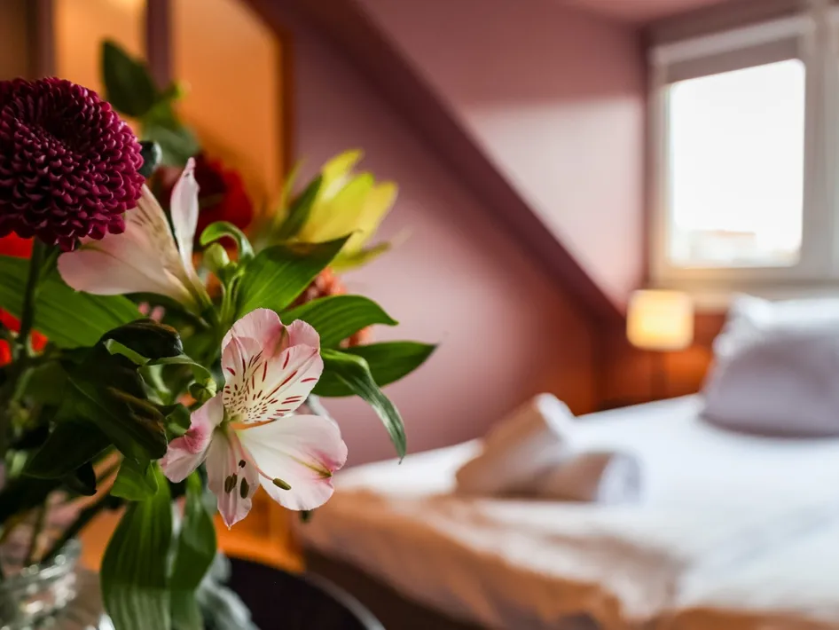 Gemütliches Hotelzimmer im B&B Willem II mit Blumen im Vordergrund und einem frisch gemachten Bett.