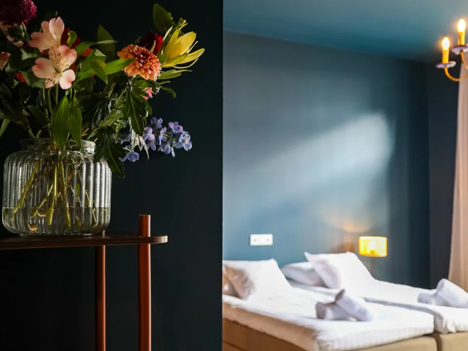 Stylishly furnished room at B&B Willem II with soft lighting and a bouquet of flowers in the foreground.