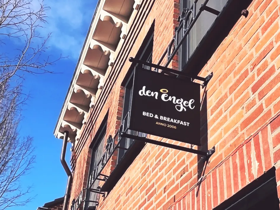 Gevel van B&B den Engel met herkenbaar zwart uithangbord tegen een bakstenen muur.