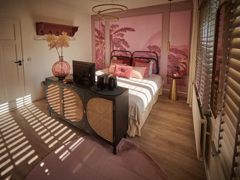 Sfeervolle slaapkamer met roze muren en decoraties, onderdeel van B&B den Engel.