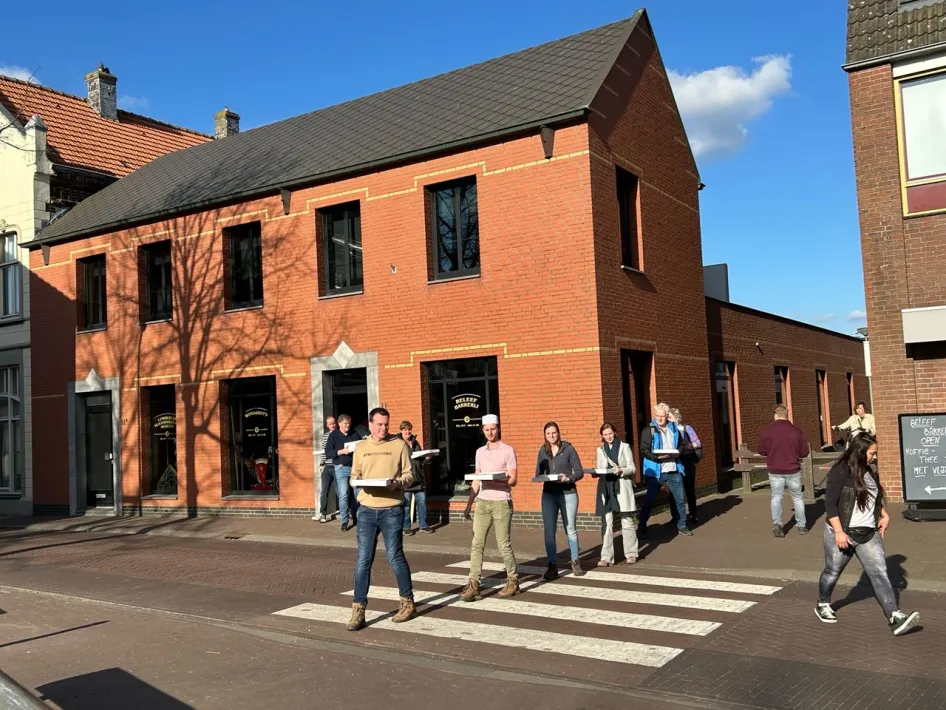 The front of Gerards-Steeghs Bakery & Baking Experience in Horst with a group of visitors standing on the pavement, having just finished a vlaai baking workshop and ready to take their own vlaaien home.