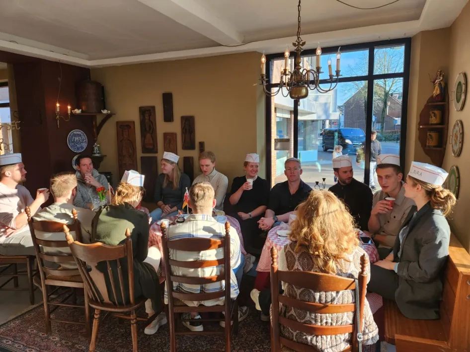 Eine Gruppe Menschen sitzt bei Kaffee und Vlaai während einer gemütlichen Pause in der Erlebnisbäckerei Gerards-Steeghs am Tisch.