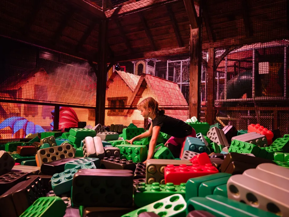 A girl plays among large green, red and black building blocks in the indoor play area of Billybird Dragon Village.