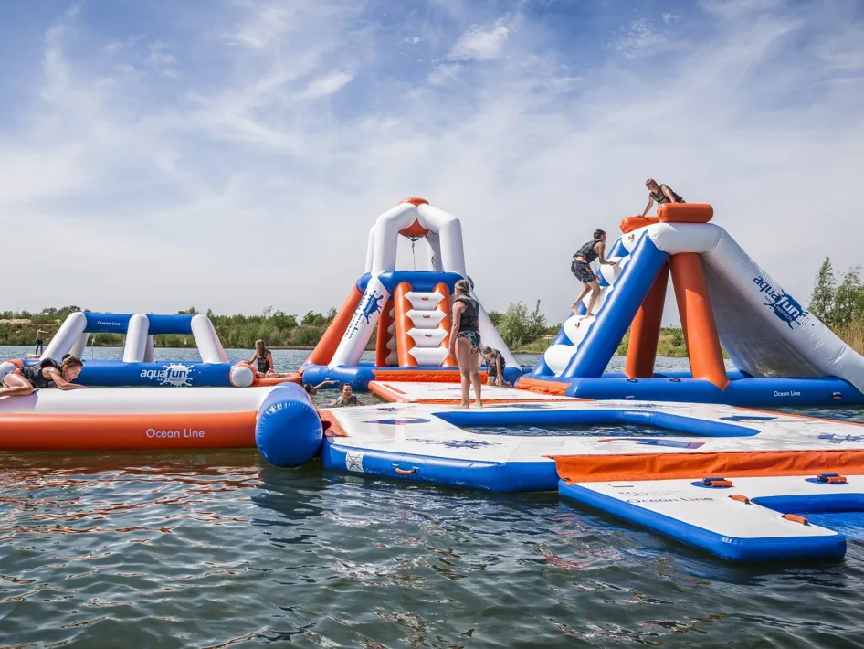 Kinderen spelen op het drijvende AquaFunPark in het water bij BillyBird Drakenrijk.
