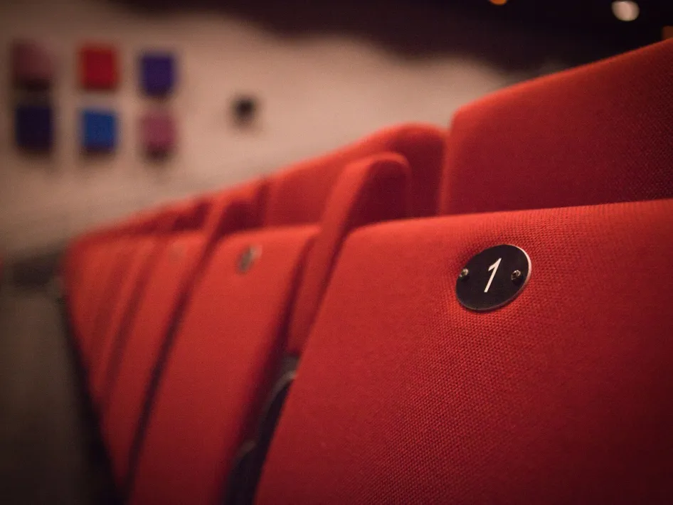 Close-up van een rode theaterstoel met stoelnummer 1 in een lege zaal van de Bombardon 