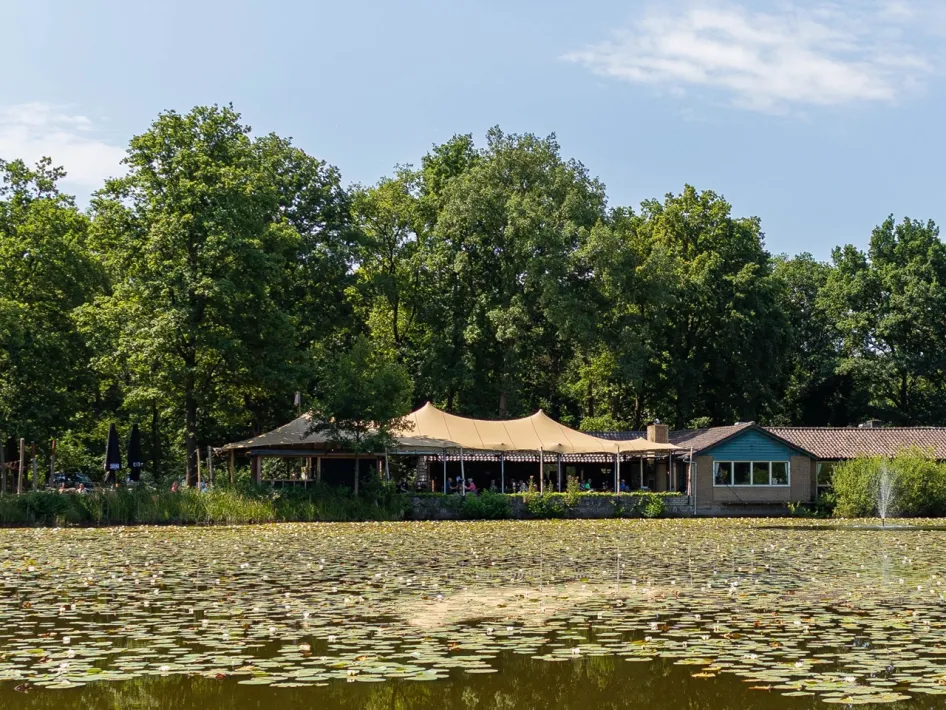 Boshuys Nieuw Vosseven mit Terrasse an einem Weiher voller Seerosen, umgeben von Bäumen, mit Gästen, die draußen in grüner Umgebung sitzen