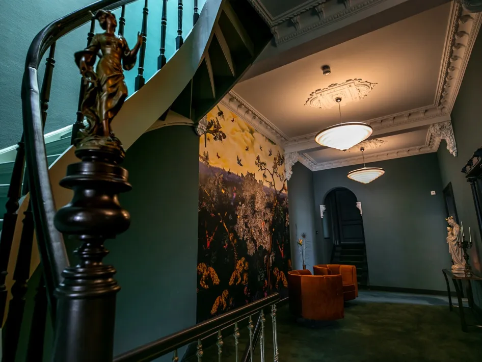 Entreehal van Boutique Hotel N10 met trap, ornamentenplafond en kunst aan de muur