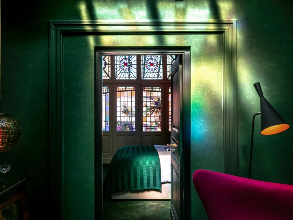 Blick in ein Schlafzimmer mit Bleiglasfenstern und warmem Lichteinfall