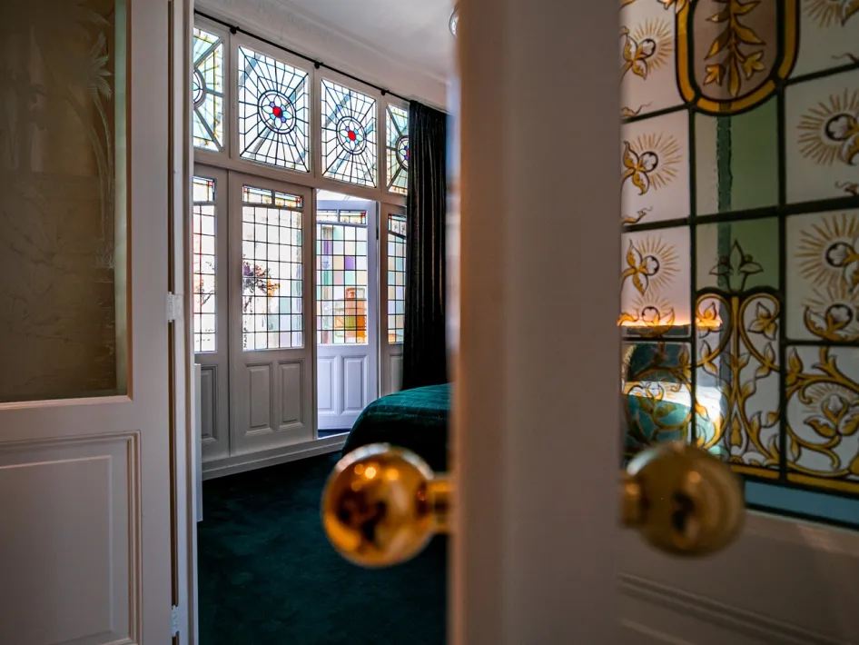 Schlafzimmer mit farbenfrohen Wänden und Bleiglasfenstern im Boutique Hotel N10