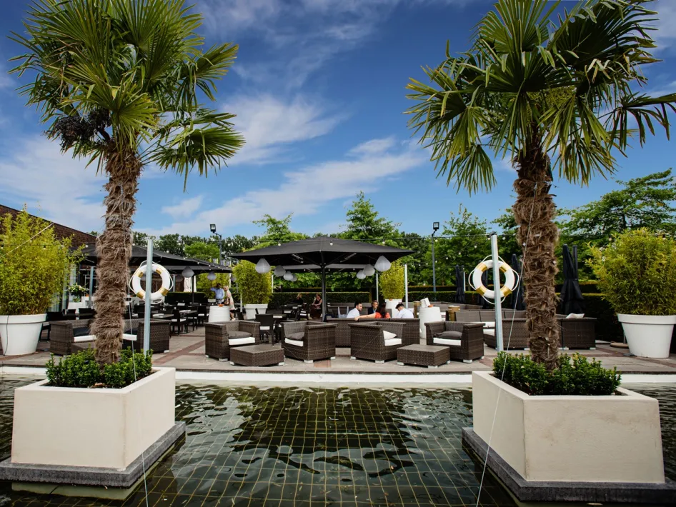 Lounge area of Brasserie Boschmolenplas with palm trees, seating and water feature