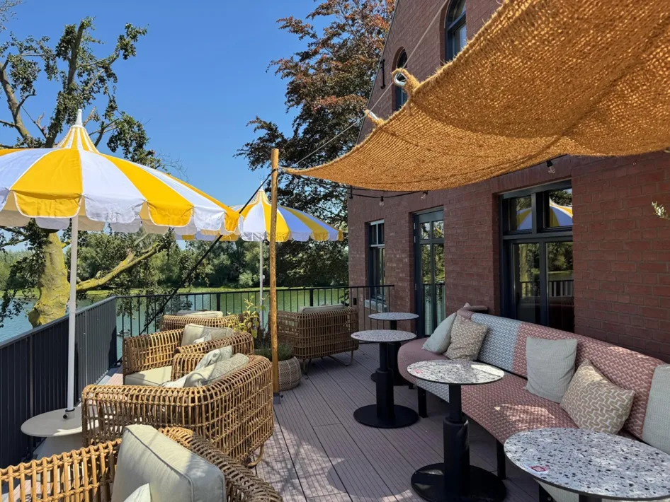 Dakterras LUS SOLEIL met rotan stoelen, gele parasols en uitzicht over de Maas.