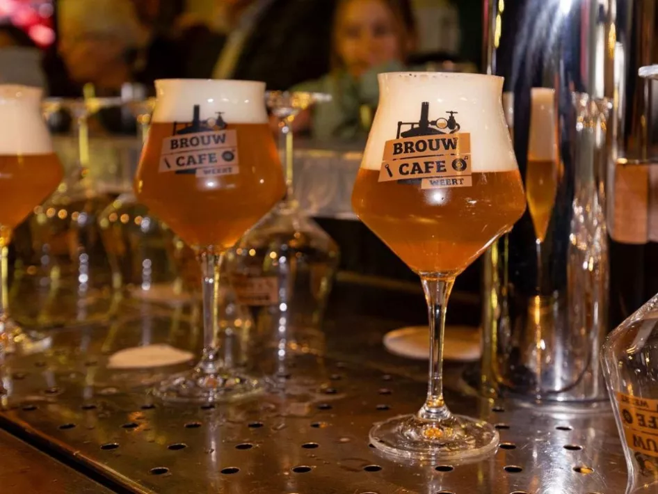 Glazen gevuld met ambachtelijk gebrouwen bier, voorzien van het logo van Brouwcafé Weert, klaar om geserveerd te worden aan de bar.