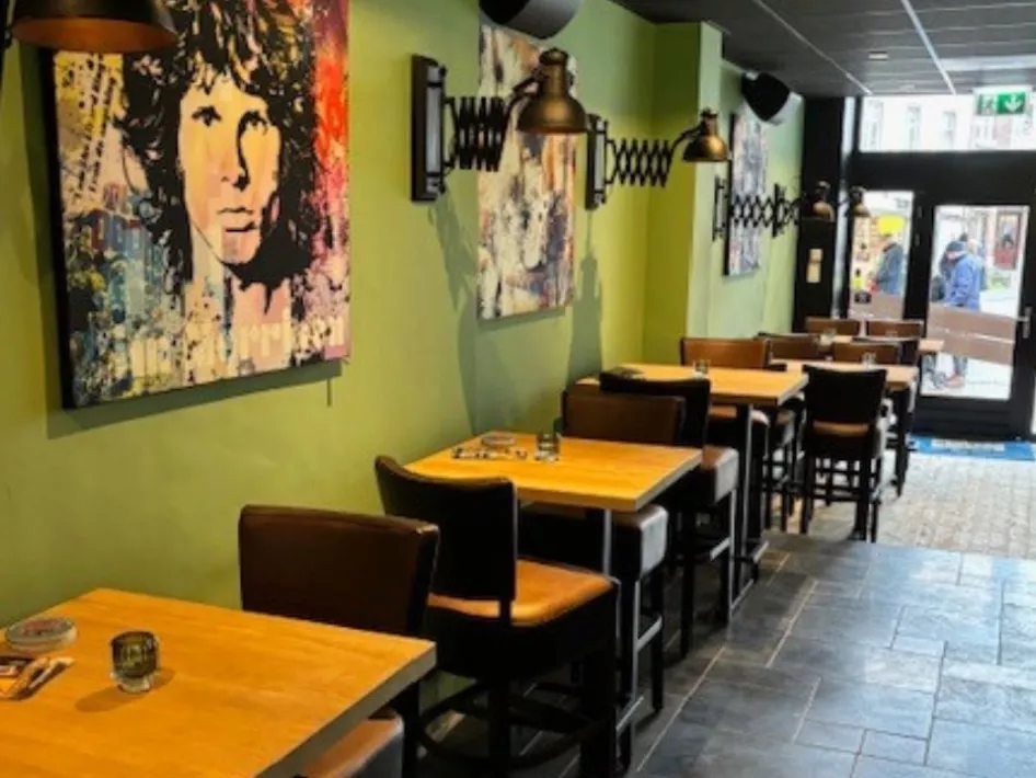 Een sfeervolle ruimte met houten tafels, leren stoelen en grote schilderijen van iconische muzieklegendes.