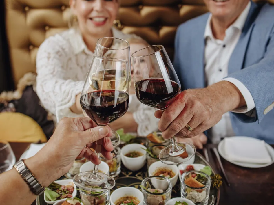 Gasten proosten met rode en witte wijn tijdens een shared dining-ervaring bij Bubbles & Bites.