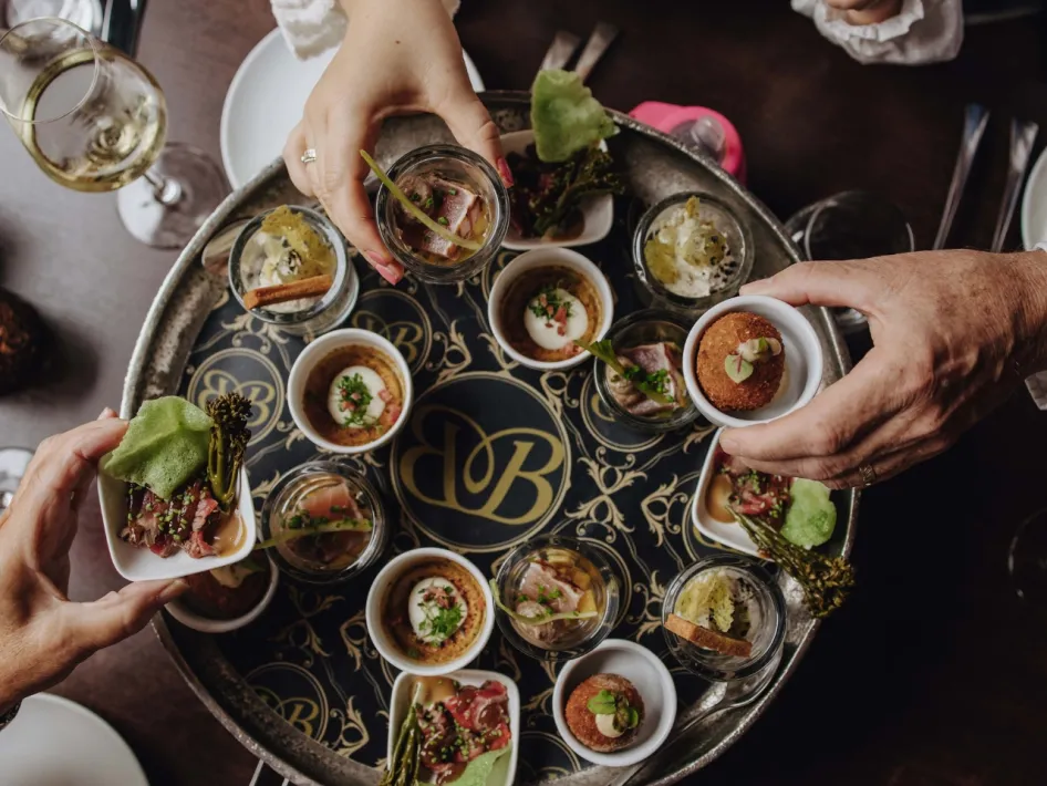 A richly filled platter of sophisticated small dishes is shared at the table at Bubbles & Bites.