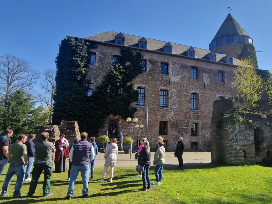 Frau macht eine Führung in authentischer Kleidung vor dem Burg Brüggen
