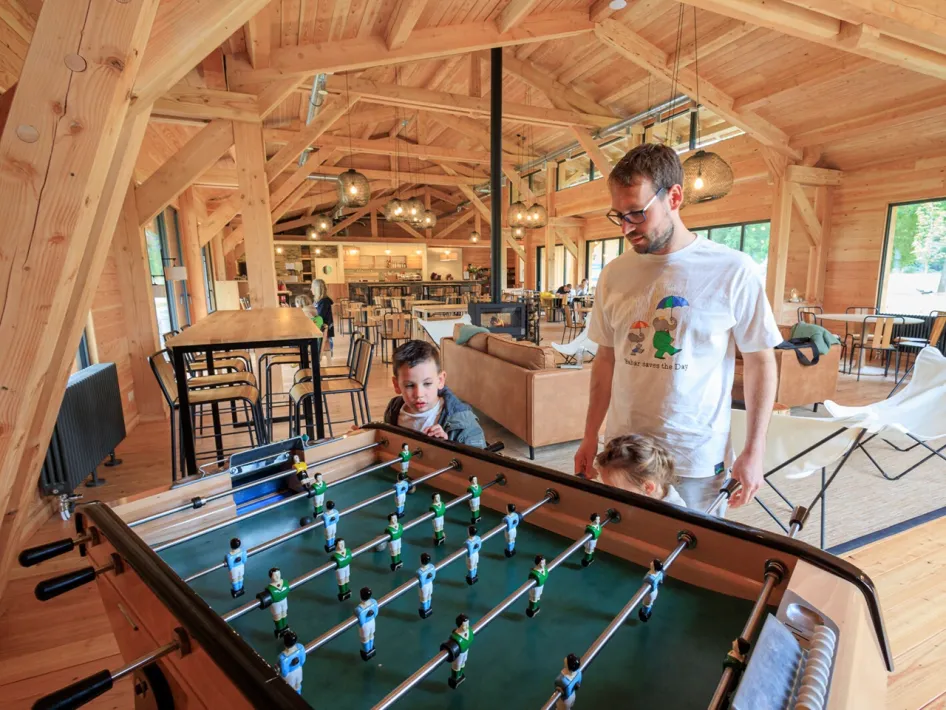 Children playing table football in the wooden recreation room with seating areas