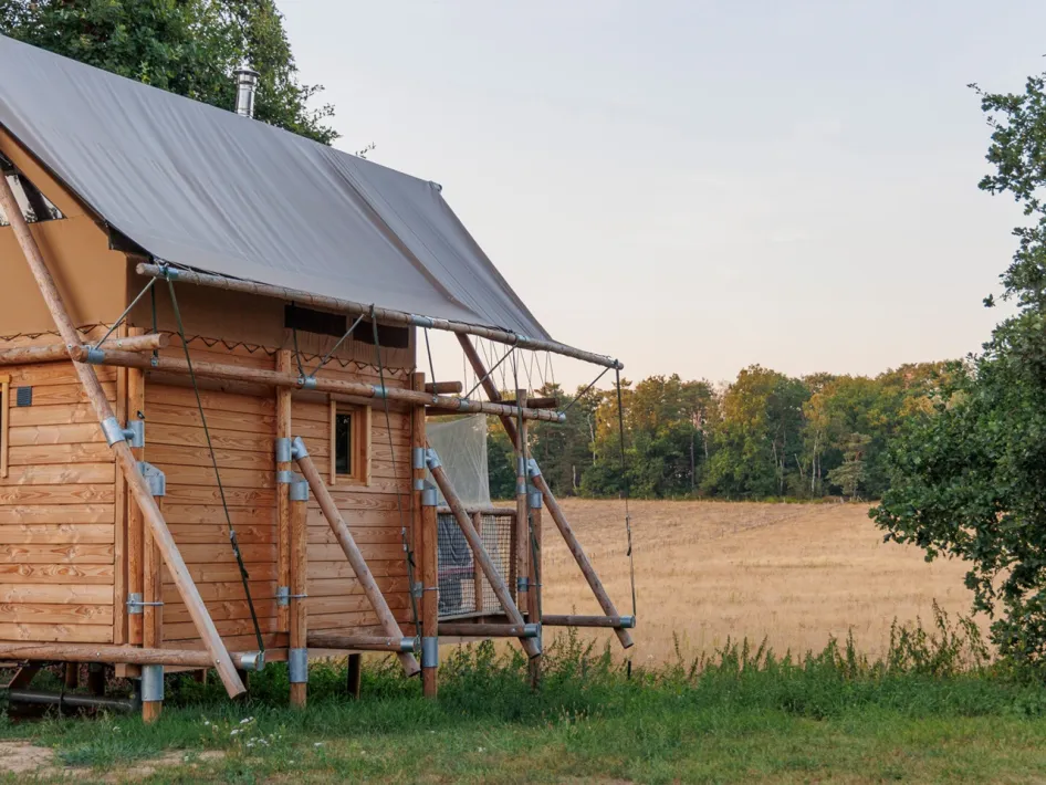 Glamping tent on the edge of an open field with a view of nature