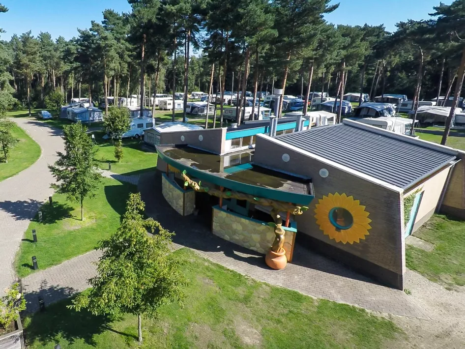 Een overzicht van het sanitair gebouw en de omliggende kampeerplaatsen