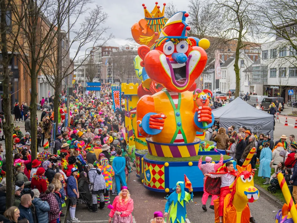 A busy street full of carnival revellers in festive outfits admire the impressive floats during the Carnival Parade Weert.