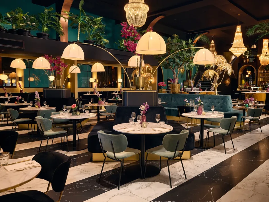 Interieur des Cerise Restaurant mit gedeckten Tischen, grünen Sitzbänken, Blumen und warmer Beleuchtung.
